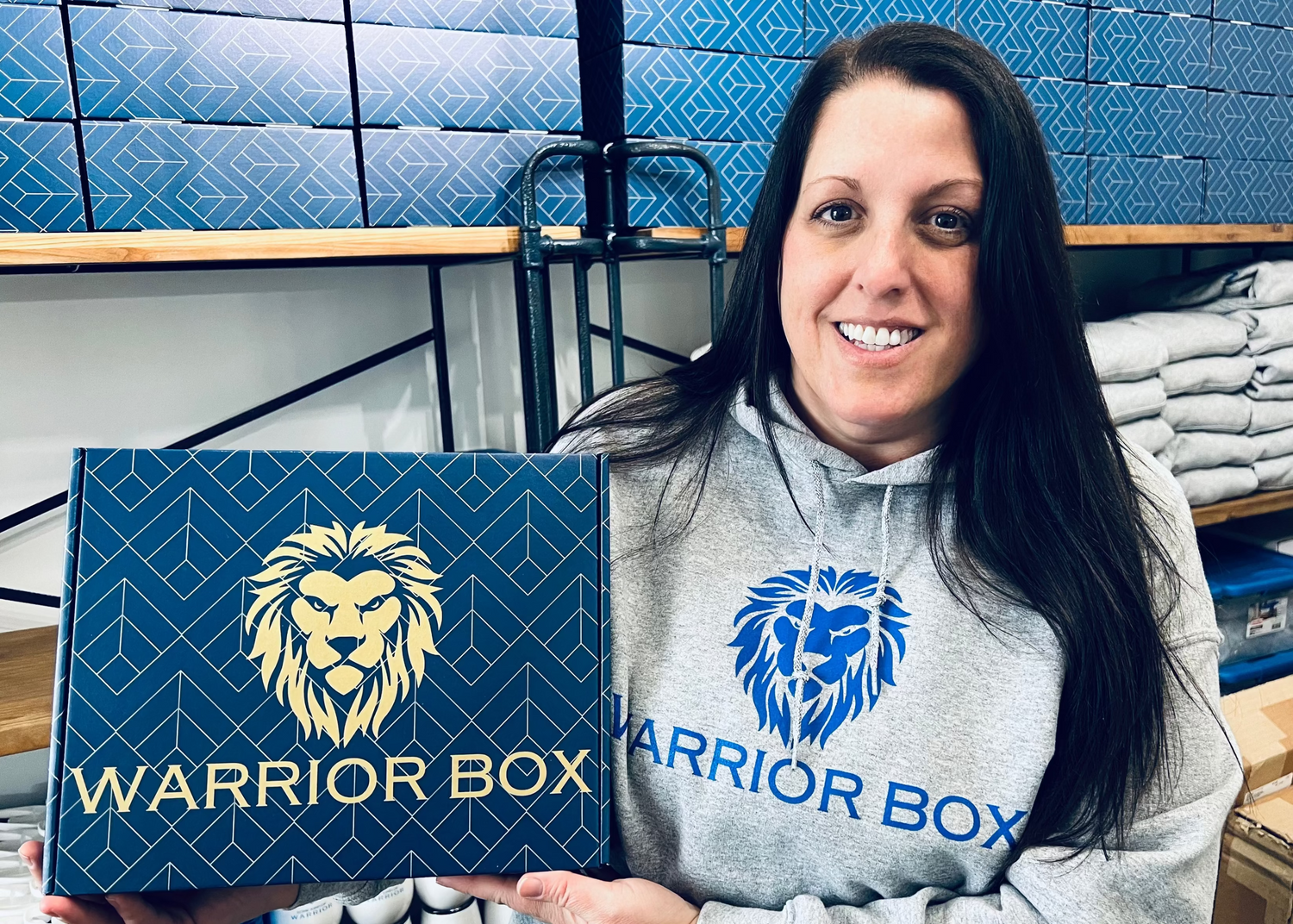 Woman holding a 'Warrior Box' in a warehouse setting